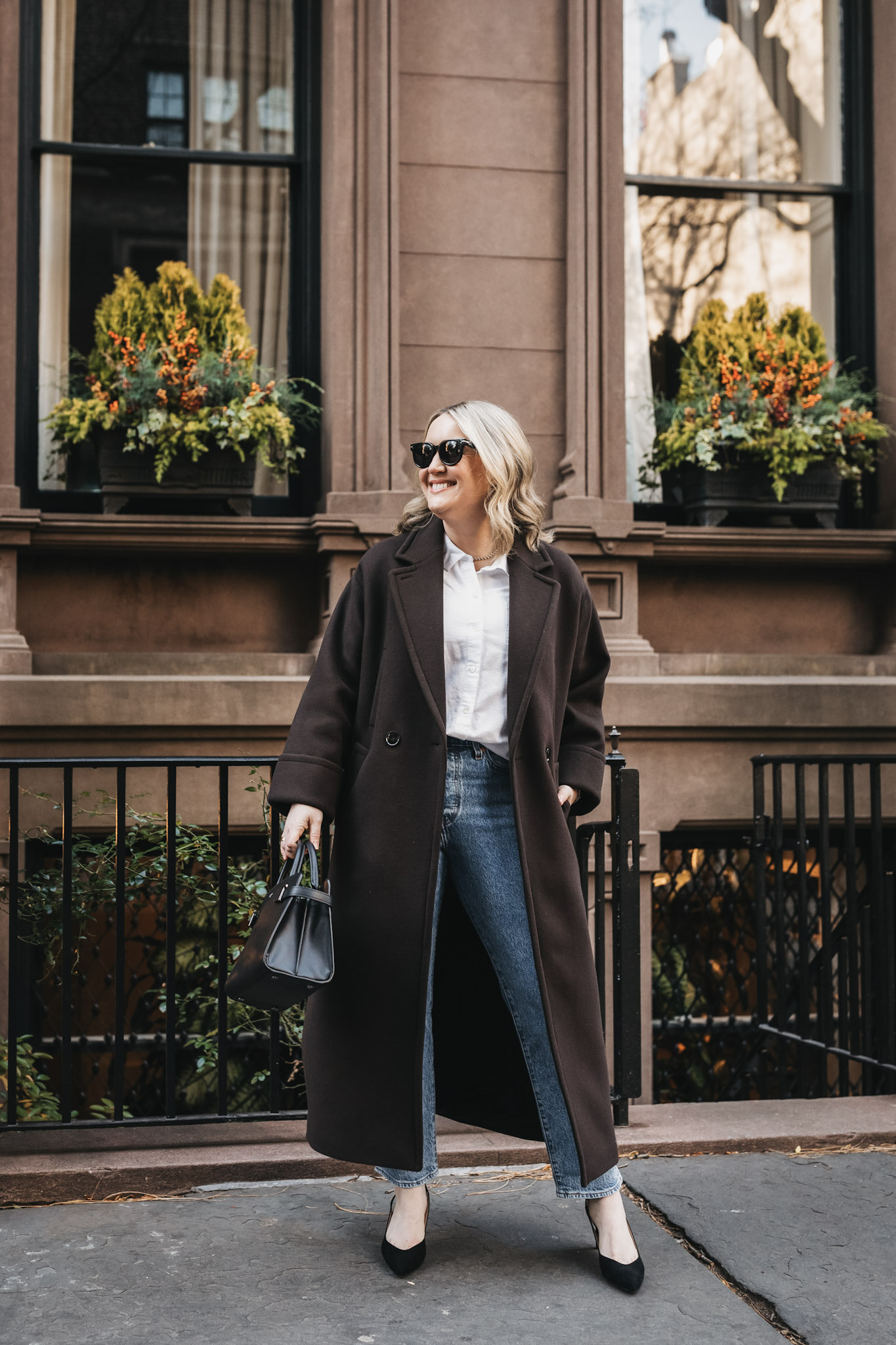 Wit Whimsy wearing brown coat, white button shirt 