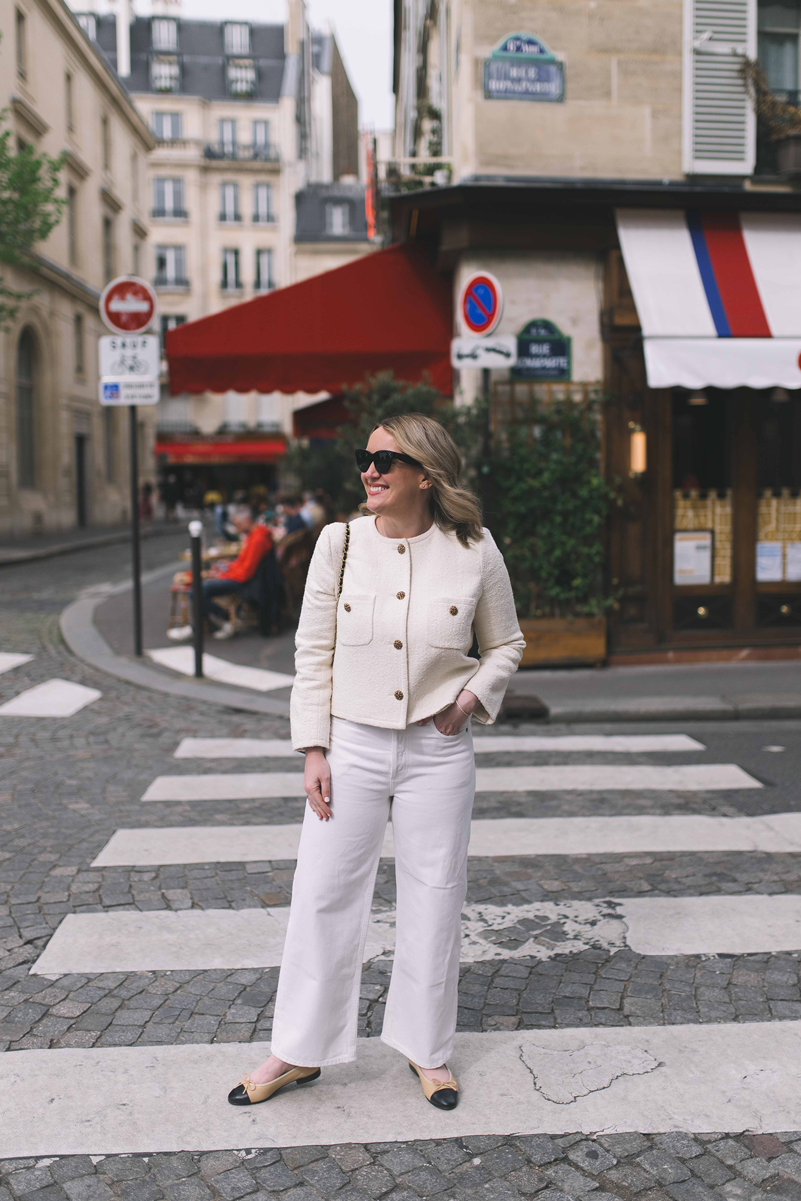 Woman wearing a cream lady jacket, white wide-leg denim and ballet flats on a chic European city street, ideal summer outfit inspiration for London.