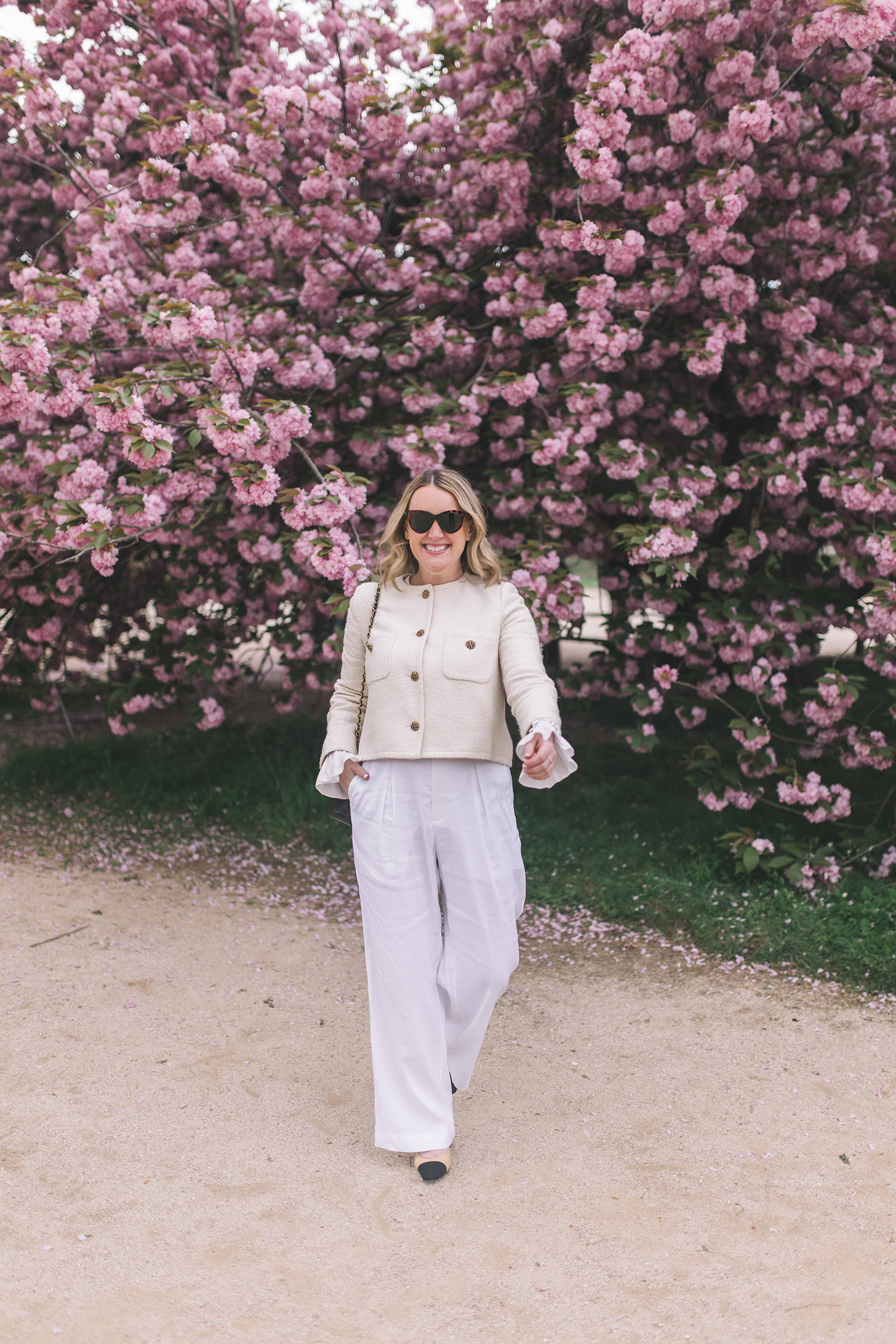 Woman wearing a cream lady jacket and white linen trousers, chic lightweight outfit idea for London in summer.