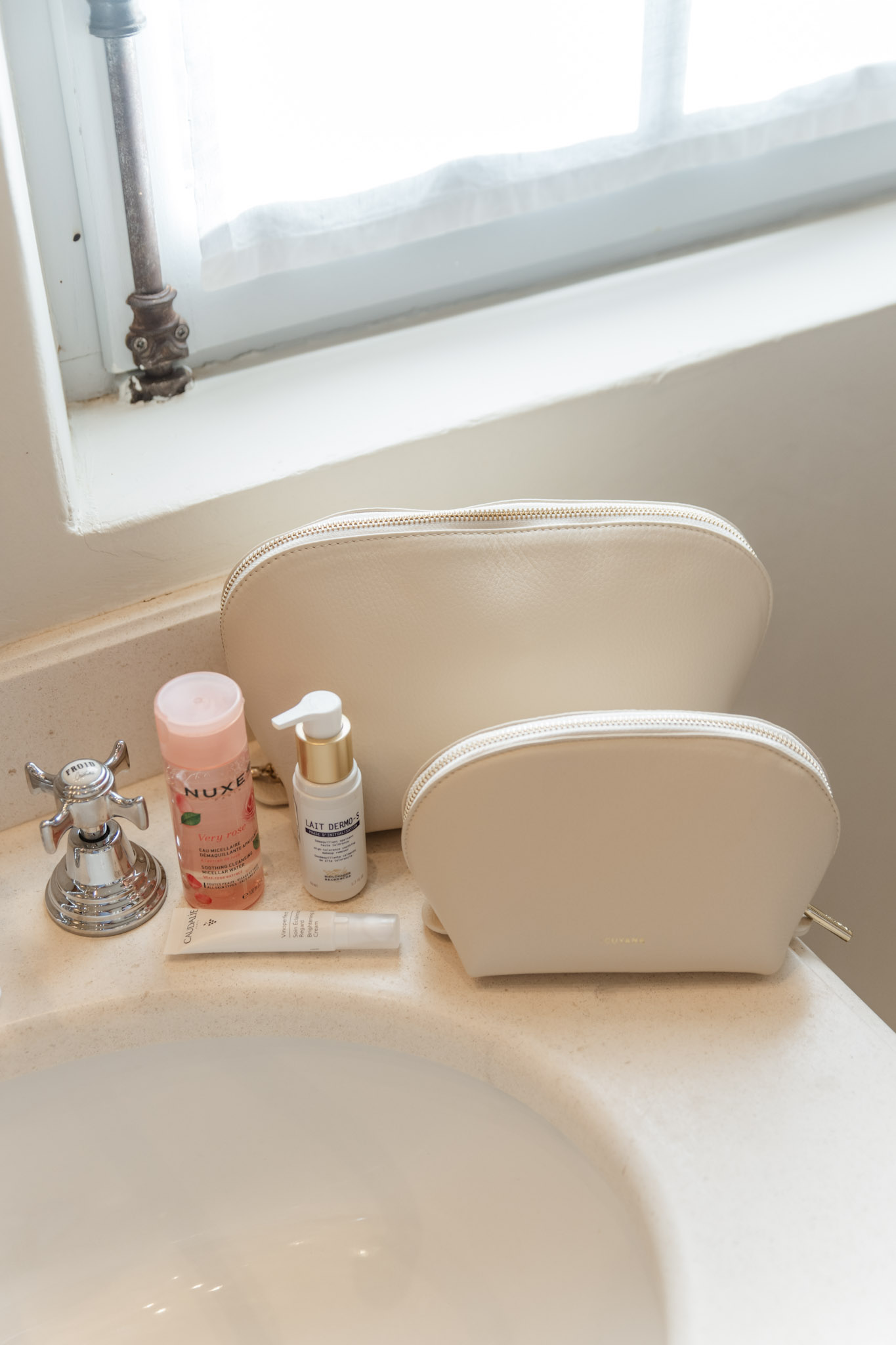 cosmetics bags and skincare bottles on a bathroom vanity | Best French Pharmacy Skincare for Mature Skin